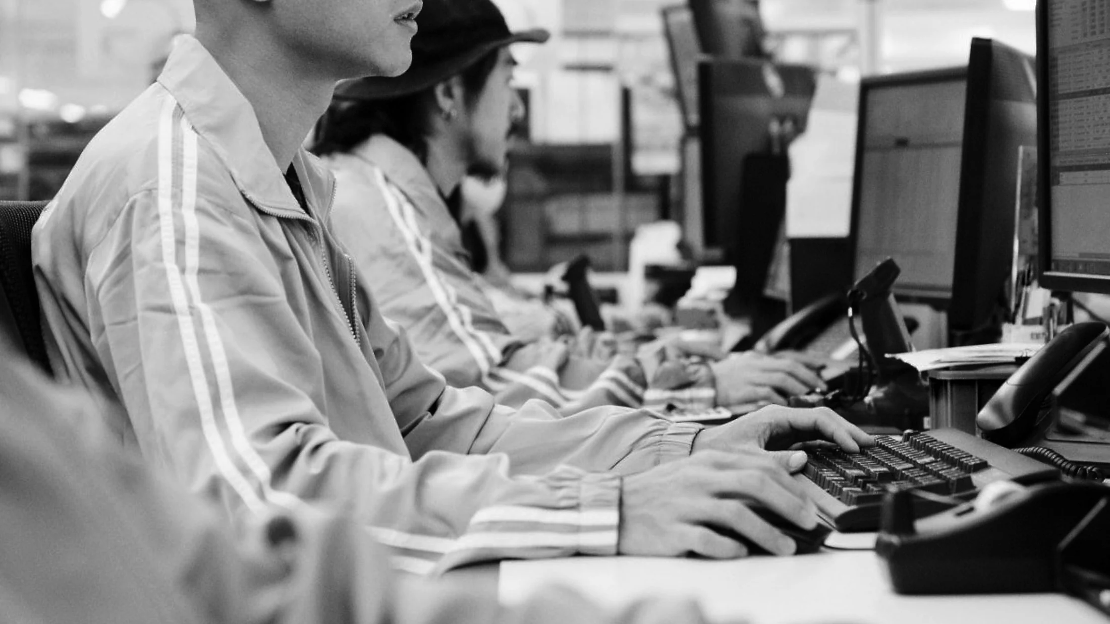 Team in grey-and-white workwear at rows of desks in an open-space office