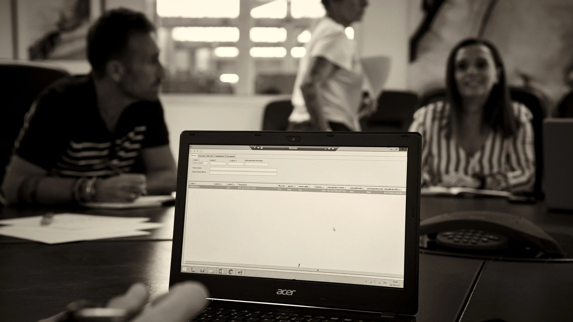 Team discussing operational data on a laptop screen during a working meeting, black and white