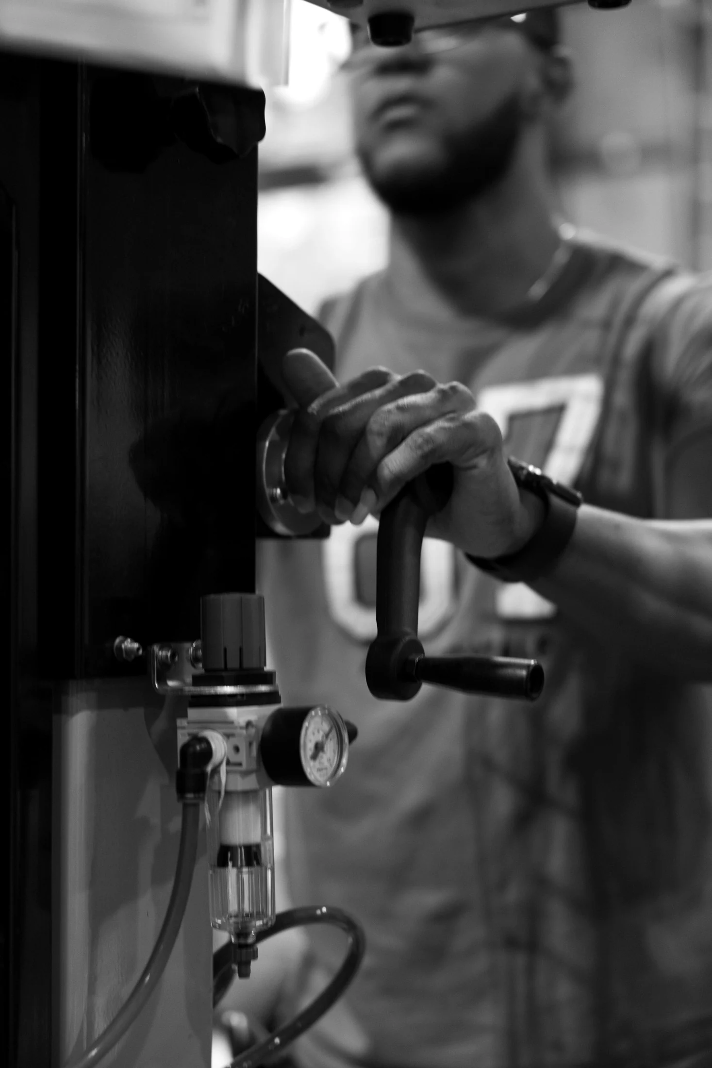 Operator engages the lever of an industrial pneumatic control panel with a pressure gauge, close-up view
