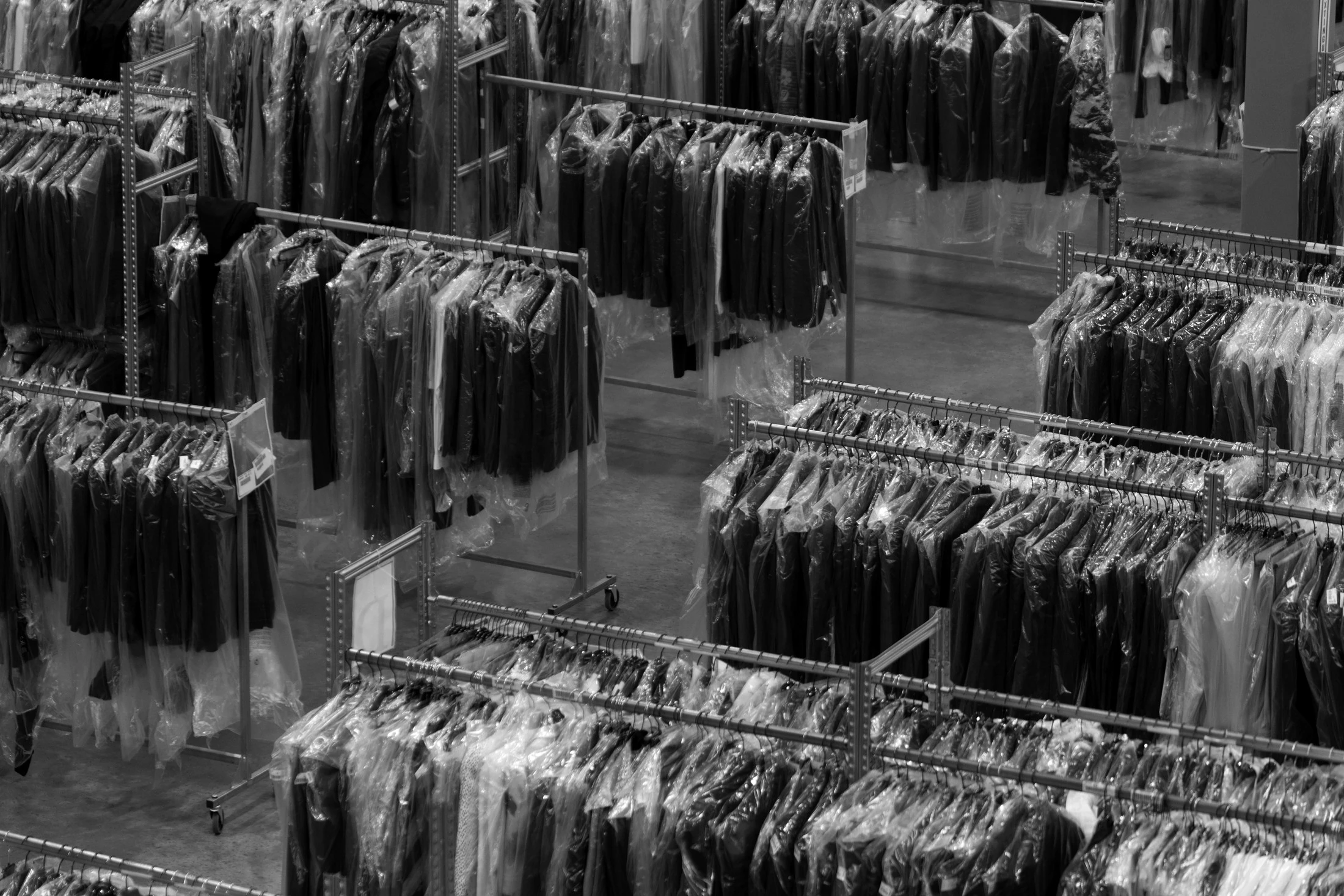 Overhead view of dense rows of garments hanging in protective plastic covers across warehouse racking