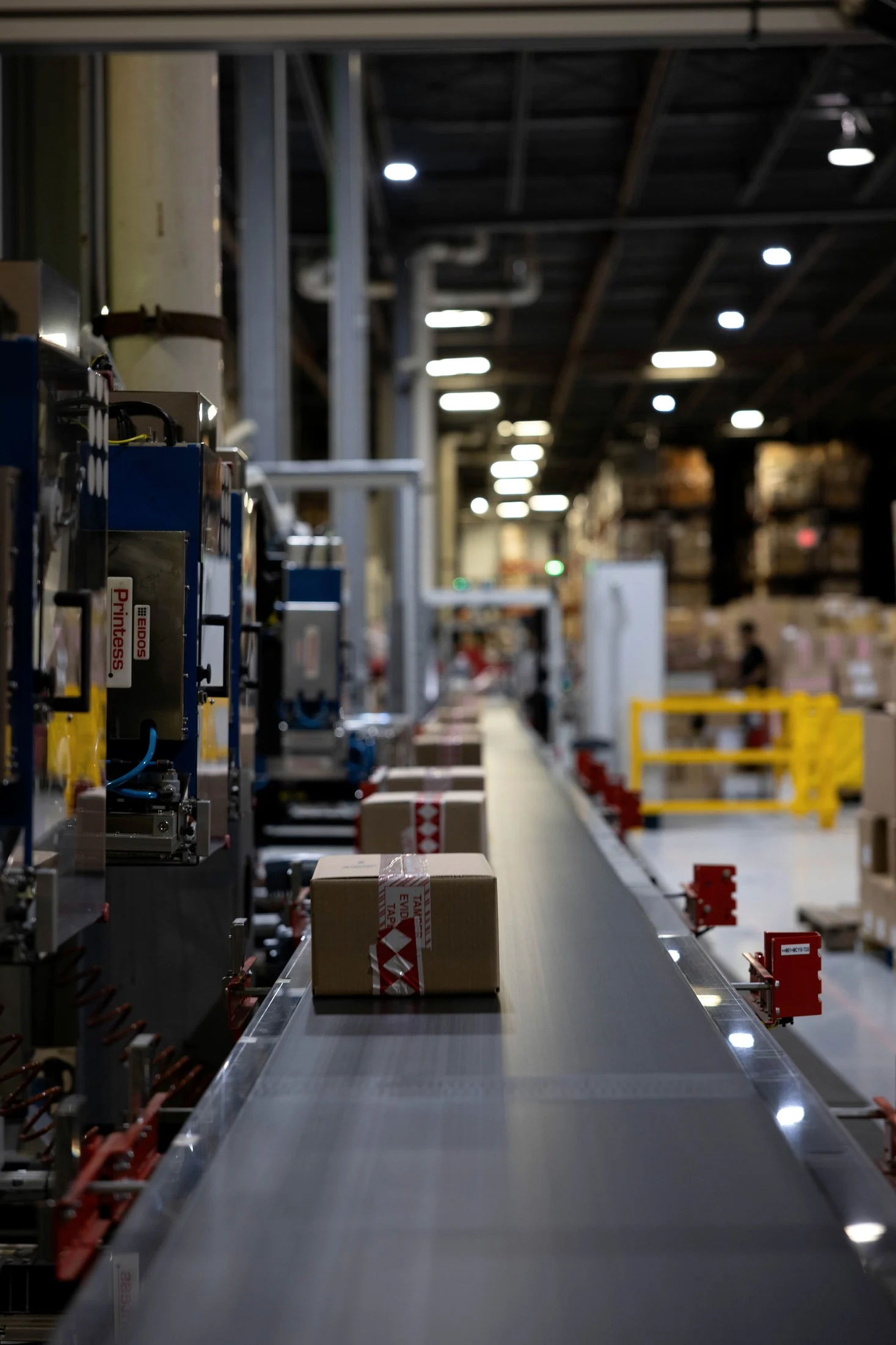 Automated labelling equipment and conveyor line with tamper-evident tape on outgoing parcels inside a group distribution centre