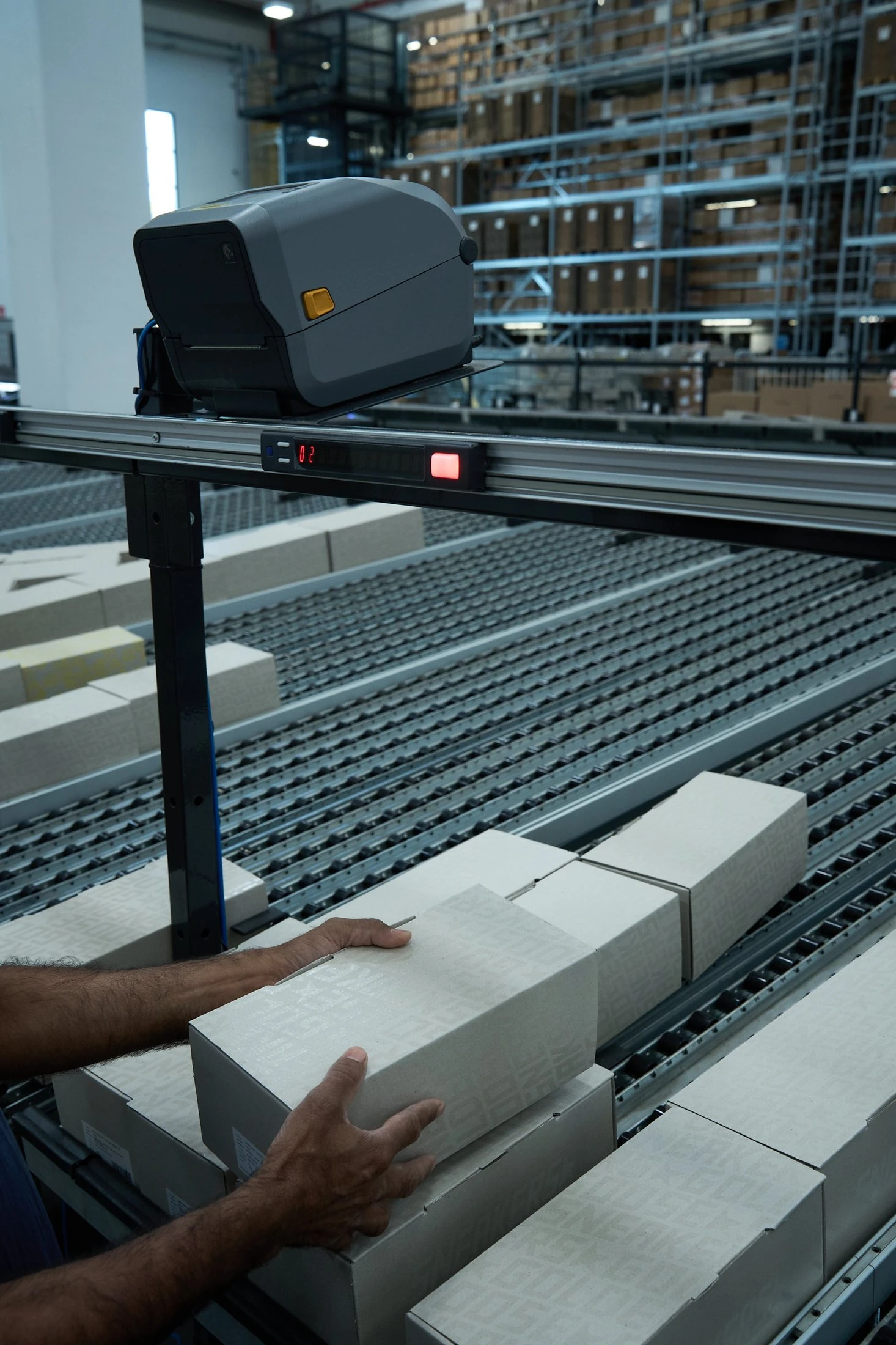Automatic label printer over a conveyor with a digital counter as an operator places a carton, in colour