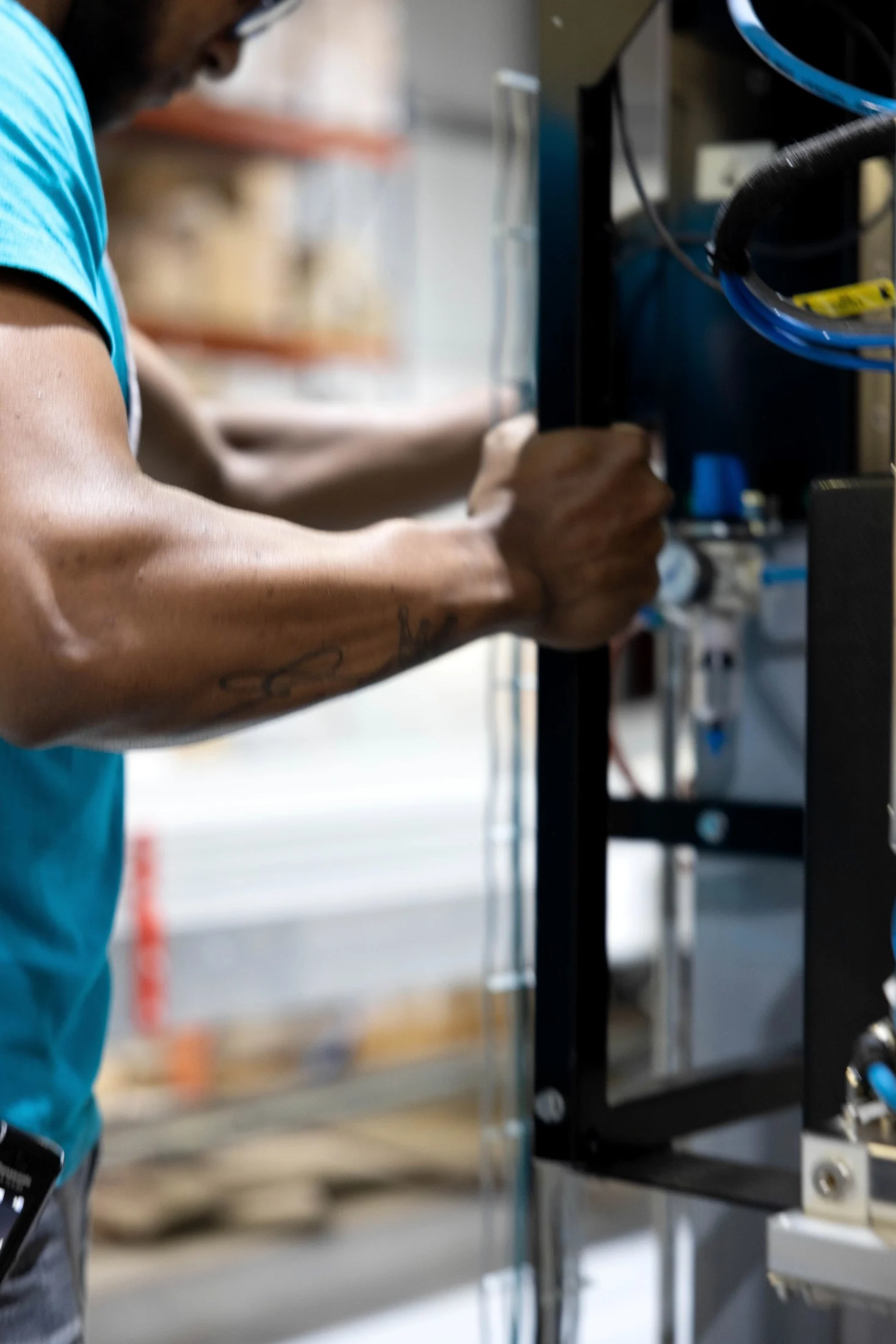Close up of an operator’s arm gripping a warehouse racking upright next to automation wiring, in colour